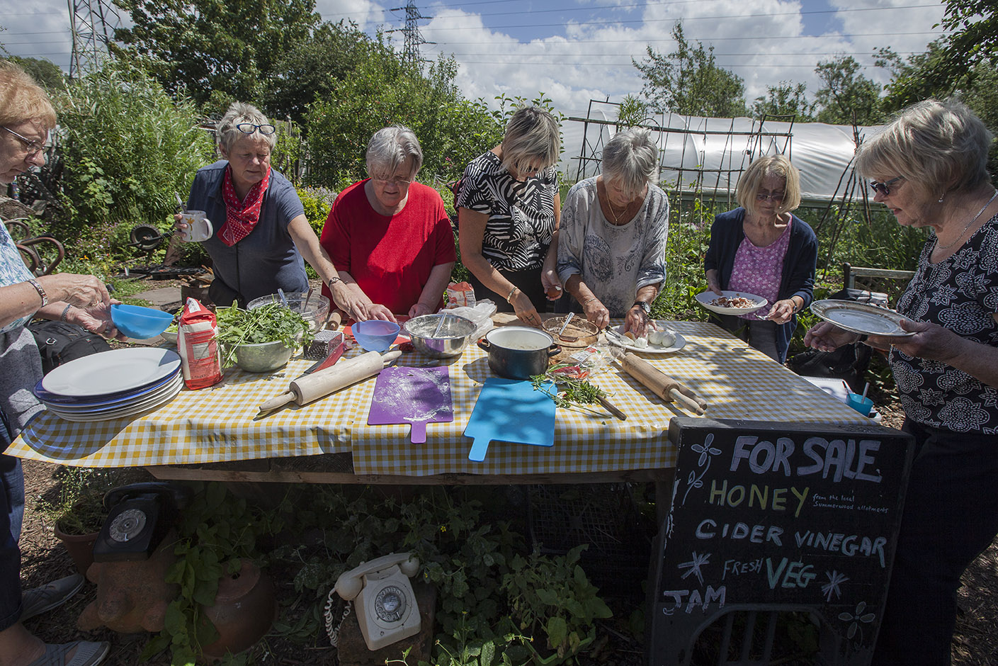People collectively making food at a large table in an allotment garden